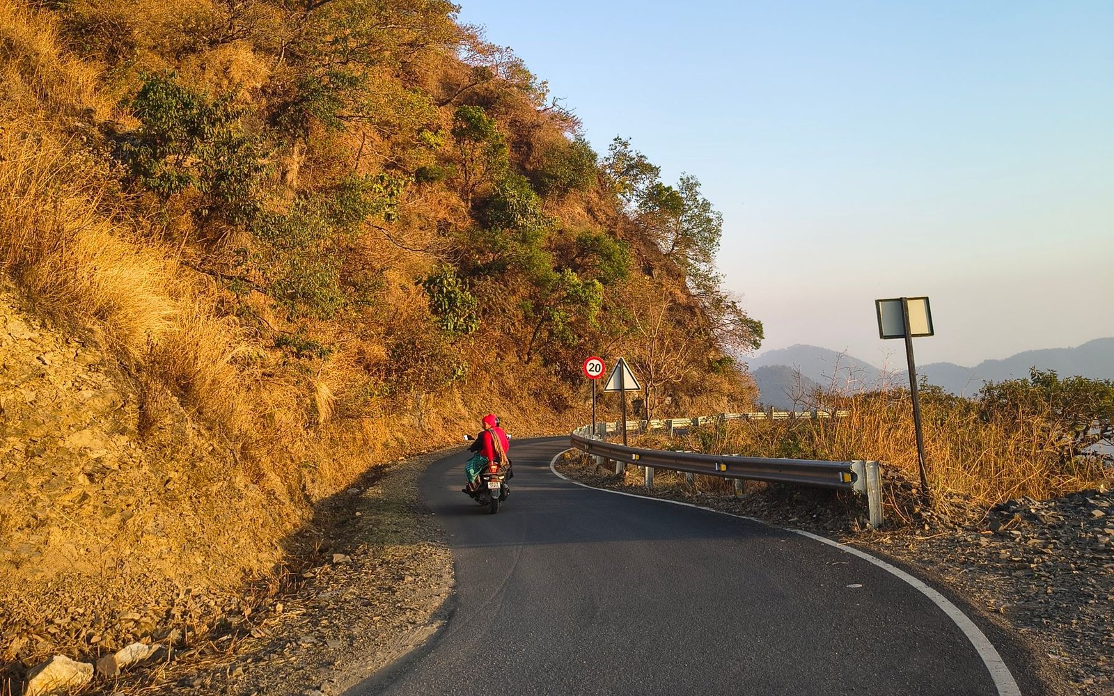 Motard sur une route de montagne au milieu des reliefs